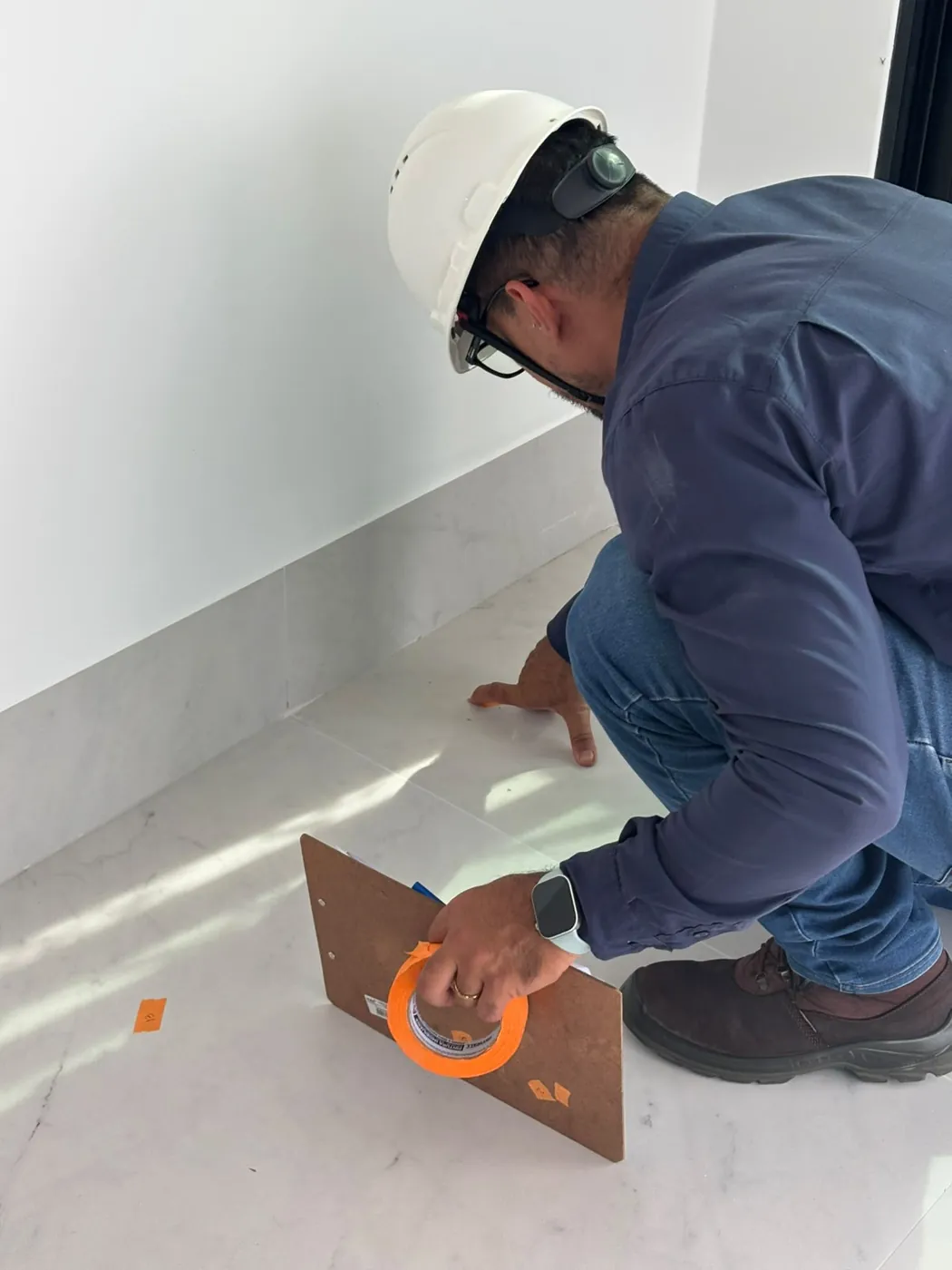 Engenheiro marcando com fita um defeito no piso