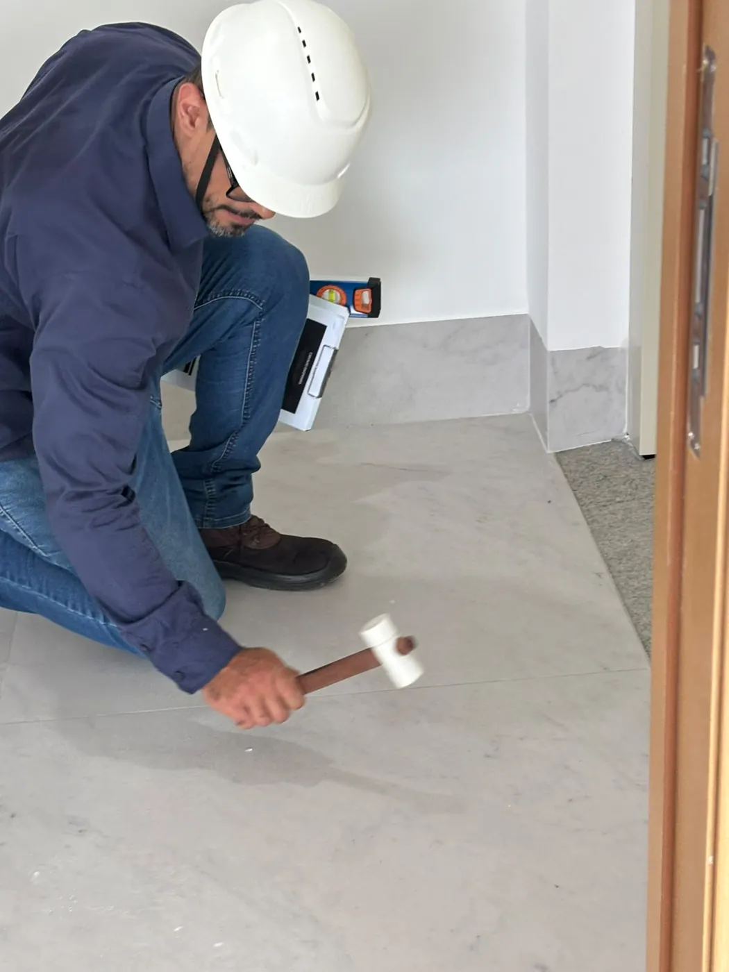 Engenheiro batendo levemente no porcelanato com martelo de borracha