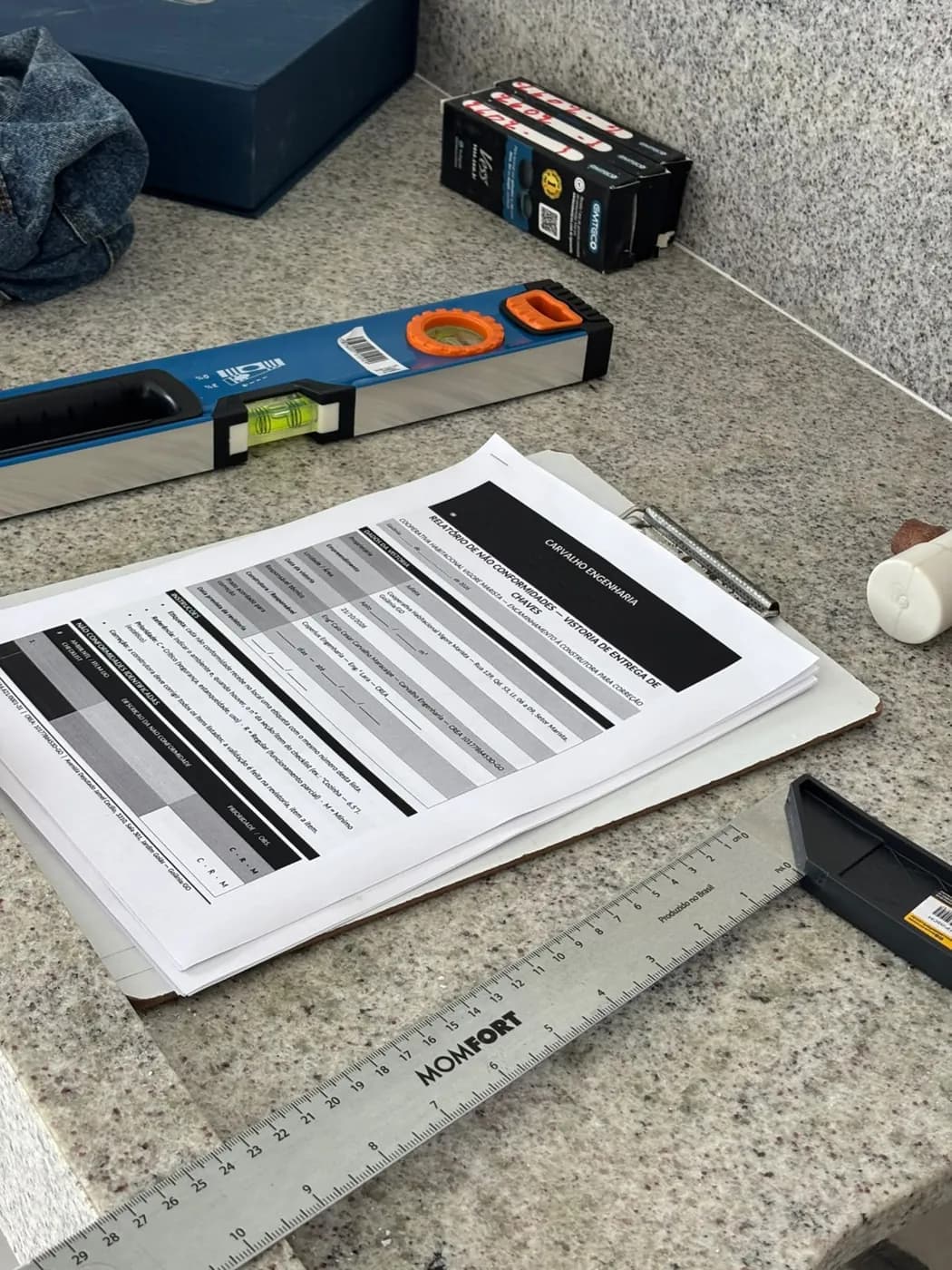 Régua de alumínio, nível e checklist da vistoria sobre a bancada